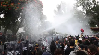 Protesters stand near state riot police as a water cannon is used during clashes at a demonstration demanding clean water, after weeks of residents' complaints about discolored and foul-smelling water in parts of the metropolitan area, outside Casa Jalisco, the official residence of the state governor, in Guadalajara, Mexico, October 11, 2026. REUTERS/Stringer