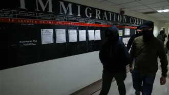 Masked federal agents walk in a hallway at the New York Federal Plaza Immigration Court inside the Jacob K. Javitz Federal Building in New York on December 22, 2025. US President Donald Trump has made deporting undocumented immigrants a key priority for his second term, after successfully campaigning against an alleged "invasion" by criminals. (Photo by CHARLY TRIBALLEAU / AFP)