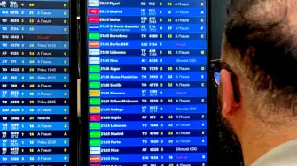 Un viajero consulta un panel de información de vuelos.