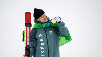 Lucas Pinheiro Braathen mira su medalla en el podio del evento de esquí alpino de eslalon gigante masculino.