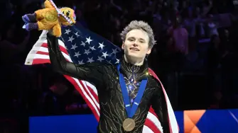 El estadounidense Ilia Malinin celebra con la bandera de Estados Unidos tras ganar el programa libre masculino del Campeonato Mundial de Patinaje Artístico.