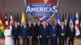 US President Donald Trump (C) stands with, (L/R), Trinidad and Tobago's Prime Minister Kamla Persad-Bissessar, Santiago Peña, President of the Republic of Paraguay, Luis Abinader, President of the Dominican Republic, Rodrigo Paz Pereira, President of Bolivia, Nayib Bukele, President of El Salvador, Javier Milei, President of Argentina, José Raúl Mulino, President of Panama, Mohamed Irfaan Ali, President of Guyana, Nasry Tito Asfura, President of Honduras, Rodrigo Chaves Robles, President of Costa Rica, José Antonio Kast, President-elect of Chile, and Daniel Roy Gilchrist Noboa Azín, President of Ecuador, during a group photograph at the start of the "Shield of the Americas" Summit at Trump National Doral in Miami, Florida, March 7, 2026. President Trump is hosting a dozen right-wing leaders from Latin America and the Caribbean to discuss issues facing the region, from organized crime to illegal immigration. The summit also aims to serve Washington by boosting US interests in the region and curbing those from foreign powers like China. (Photo by SAUL LOEB / AFP)