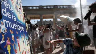 Los peatones se refrescan bajo un rociador de agua instalado por el Ayuntamiento de París durante la 45.ª edición de la Fiesta de la Música.