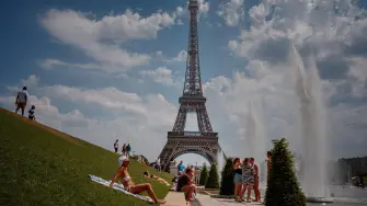 Personas se refrescan cerca de la fuente del Trocadero, con la Torre Eiffel de fondo.