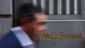 Un hombre pasa junto a una señalización de Wall Street frente al edificio de la Bolsa de Valores de Nueva York.