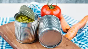 Two cans of boiled green peas, vegetables and tablecloth on a white and marble background. High quality photo