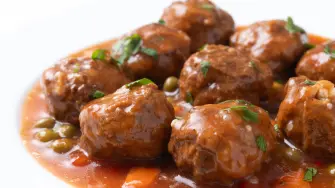 Meatballs, green peas and carrot with tomato sauce isolated on white background