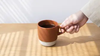 Woman getting a coffee cup from a wooden table