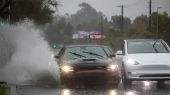 Un automóvil circula por una carretera inundada en el bulevar La Cienega el 24 de diciembre de 2025 en Los Ángeles, California.