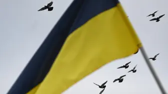 Birds fly in the sky over Ukrainian flag at the Lychakiv cemetery on the Day of the Armed Forces of Ukraine in Lviv on December 6, 2025, amid the Russian invasion of Ukraine. (Photo by YURIY DYACHYSHYN / AFP)