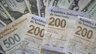 (FILES) Picture of Venezuelan bolivar and US dollar bills taken in Caracas on September 30, 2025. On December 31, 2025, the Central Bank of Venezuela (BCV) valued the dollar at 301.37 bolivars (Venezuelan currency), a price valid until January 2, representing an increase of 479.25% compared to the 52.02 bolivars set by the issuing entity at the beginning of 2025. (Photo by Federico PARRA / AFP)