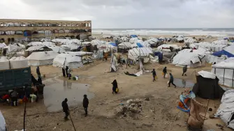 Displaced Palestinians carry jerricans amid tent shelters set up along the shore in Gaza City as strong winter winds sweep the Palestinian enclave on January 13, 2026. A fragile ceasefire has been in place since October, following a deadly war waged by Israel in response to Hamas's unprecedented October 7, 2023 attack on Israel. Nearly 80 percent of buildings in Gaza have been destroyed or damaged by the war, according to UN data. (Photo by Omar AL-QATTAA / AFP)