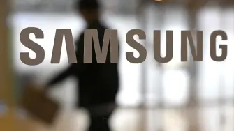 A man walks past the logo of Samsung Electronics displayed on a glass door at the company's Seocho building in Seoul on January 29, 2026. South Korean tech giant Samsung Electronics posted record quarterly profits on January 29, riding strong market demand for its artificial intelligence chips. (Photo by Jung Yeon-je / AFP)