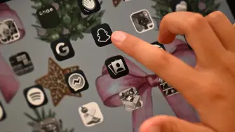 10-year-old Bianca Navarro points an icon of Snapchat at her home in western Sydney on December 10, 2025. Australia banned young teenagers from social media on December 10, launching a world-first crackdown designed to unglue children from addictive scrolling on the likes of Facebook, Instagram and TikTok. (Photo by Saeed KHAN / AFP)