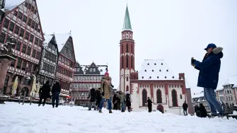 People take pictures of the snow-covered Roemer square in Frankfurt am Main, western Germany, on January 26, 2026 as the air temperature reached 1 degrees Celsius above zero. (Photo by Kirill KUDRYAVTSEV / AFP)