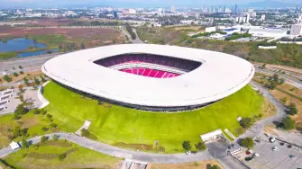 Zapopan, Mexico - December 7: Aerial drone view of modern Akron Stadium in Guadalajara, showing its distinctive white roof, red seats, green landscape, and urban areas
