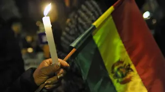 A woman holds a candle and a Bolivian national flag during a vigil in homage of victims of clashes between supporters of defeated presidential candidate Carlos Mesa and supporters of the ruling Movimiento Al Socialismo (MAS) party in La Paz, on November 1, 2019. President Evo Morales called Thursday for a "truce" while an international body conducts an audit of Bolivia's disputed election results, after clashes between rival groups left two dead and nearly 140 injured. (Photo by JORGE BERNAL / AFP)