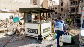 Hombre iraní con bolsas mientras camina entre los escombros.