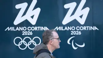 Un hombre pasa junto al logo de los Juegos Olímpicos y Paralímpicos Milán-Cortina 2026 en Milán.