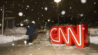 (FILES) The CNN logo is seen as snow falls outside the fifth Republican presidential primary debate at Drake University in Des Moines, Iowa, on January 10, 2024. Paramount Skydance chief David Ellison sought on March 5, 2026, to calm fears over the future of CNN, pledging to protect the news network's editorial independence as his company closes in on a landmark takeover of Warner Bros. Discovery. "CNN is an incredible brand with an incredible team, and we absolutely believe in the independence that needs to be maintained, obviously for those incredible journalists, and we want to support that going forward," Ellison told CNBC. (Photo by Christian MONTERROSA / AFP)