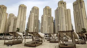 Empty beds are pictured before high-rise buildings along a beach at Jumeirah Beach Residence (JBR) in Dubai on March 11, 2026. Iran said on March 11 that it was ready for a long war of attrition that would "destroy" the world economy, after firing on two commercial ships and threatening any vessels from the US or its allies. (Photo by Fadel SENNA / AFP) /