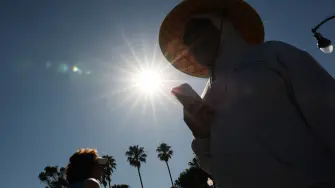 Una persona lleva un sombrero para protegerse del sol matutino mientras camina por The Strand en Redondo Beach, California.