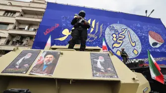 Members of the security forces stand guard on armoured vehicles plastered with portraits of Irans slain supreme leader Ayatollah Ali Khamenei (L and R) and of his son, Iran's new supreme leader Ayatollah Mojtaba Khamenei, during the funerals of Iran's Revolutionary Guards Corps (IRGC) commanders, army commanders and others killed in the early days of the United States and Israeli strikes on Iran, at Enghelab Square in Tehran on March 11, 2026. Washington launched strikes with Israel on Iran on February 28, sparking retaliatory strikes by Tehran against Israel and US bases across the Gulf region. (Photo by Atta KENARE / AFP) / Attention editors: Photo taken with approval from the Ministry of Culture and Islamic Guidance (Ershad) --AFP covers the war in the Middle East through its extensive regional network, including bureaus in Tehran, Jerusalem, and several neighboring countries. Since the start of the conflict, journalists have been working under increasingly restrictive conditions. Authorities in several countries have limited reporters' movements, photo and live video coverage from sensitive locations. Some governments and armed groups have banned images of missile or drone strikes and other security-related sites. /