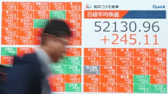 A man walks past an electronic quotation board displays numbers of the Nikkei Stock Average on the Tokyo Stock Exchange along a street in Tokyo on March 31, 2026. (Photo by Kazuhiro NOGI / AFP)