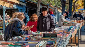 Gente revisando libros en los puestos de segunda mano en la Cuesta de Moyano de Madrid.