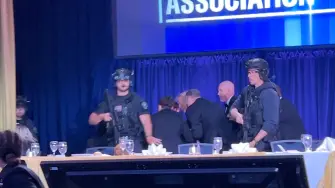 En esta captura de pantalla de un video, se ve al presidente estadounidense Donald Trump siendo escoltado fuera del recinto mientras un atacante abre fuego durante la cena anual de la Asociación de Corresponsales de la Casa Blanca en Washington