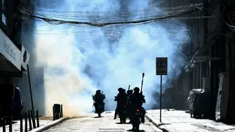 Policías antidisturbios en motocicletas persiguen a mineros entre gases lacrimógenos durante una marcha para exigir la renuncia del presidente boliviano Rodrigo Paz, en La Paz, el 14 de mayo de 2026.