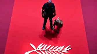 A gendarme of the canine unit patrol and a dog stand next to the logo of the 77th edition of the Cannes Film Festival inside the Grand Auditorium Louis Lumiere, ahead of the Closing Ceremony, in Cannes, southern France, on May 25, 2024. (Photo by Antonin THUILLIER / AFP)