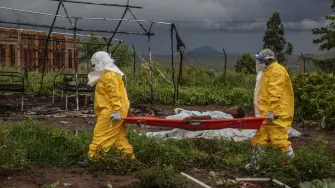 Personal médico con equipo de protección personal (EPP) traslada a un paciente en camilla en el hospital de Rwampara.