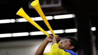 Fanático de futbol tocando una vuvuzela.