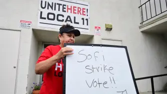 (FILES) Yolanda Fierro, a suites runner at SoFi Stadium, moves a sign into position at union headquarters where stadium workers will vote on whether to authorize a strike amid a contract dispute, days before the 2026 FIFA World Cup begins in Inglewood, California, on June 4, 2026. Workers at SoFi Stadium in Los Angeles have overwhelmingly voted to authorize a potential strike on June 6, 2026 during the World Cup, just days before football's global showpiece begins. The Unite Here Local 11 union, which represents about 2,000 stadium food and beverage workers, is demanding better pay along with assurances that federal immigration agents will not be allowed to enter the venue. (Photo by Frederic J. BROWN / AFP)