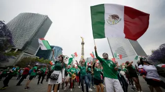 Aficionados del futbol celebrando con playeras de la Selección Mexicana en las inmediaciones del Ángel de la Independencia en la Ciudad de México.