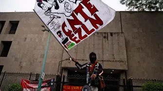 Un manifestante con una bandera del Ejército Zapatista de Liberación Nacional (EZLN) participa en una manifestación organizada por la CNTE antes del inicio de la Copa Mundial de la FIFA 2026, frente al edificio de la Secretaría de Gobernación en la Ciudad de México.