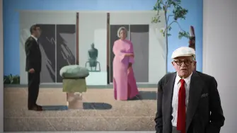 David Hockney posando frente a su obra "Fred and Marcia Weisman" en 2017. Foto: AFP