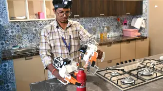 This photograph taken on May 13, 2026 shows a worker wearing a GoPro camera on his head recording actions through motion capture while filling water bottles inside a model kitchen at AI data company Objectways' office in Tamil Nadu's Karur district. Developers think feeding first-person footage, called "egocentric data", into specialised AI models will help robots copy humans. The humanoid robot market is booming, with investment bank Morgan Stanley predicting there could be over a billion in use by 2050, mostly for industrial and commercial purposes. In India, the emerging field of spatial AI is providing new employment -- for now. (Photo by R.Satish BABU / AFP)