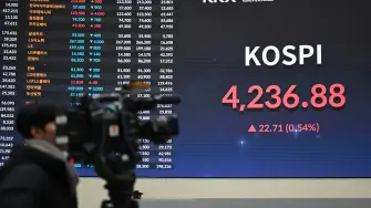 A cameraman films a stock index board showing South Korea's benchmark stock index after a ceremony celebrating the New Year's opening of the South Korea stock market at the Korea Exchange in Seoul on January 2, 2026. (Photo by Jung Yeon-je / AFP)
