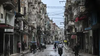 People walk along a street during a nationwide blackout in Havana on July 10, 2026. Cuba suffered its second nationwide blackout in five days on July 10 as twin energy and economic crises, compounded by a six-month US fuel blockade, caused the electricity grid to collapse. (Photo by YAMIL LAGE / AFP)