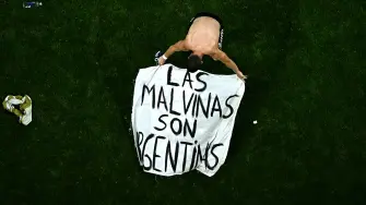 El centrocampista argentino Giovani Lo Celso, ajusta una pancarta con el mensaje "Las Malvinas pertenecen a Argentina" tras ganar el partido de semifinales del Mundial de fútbol de 2026 contra Inglaterra