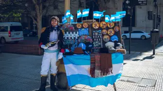 Un vendedor ofrece banderas y recuerdos de Argentina en una calle de Buenos Aires, donde el fútbol, la identidad nacional y la vida urbana se encuentran.