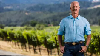 Qué mejor que leer una historia en palabras de uno de los principales actores y a 50 años de distancia, Bo Barrett, al frente de la bodega Chateau Montelena, comparte anécdotas de como uno de sus vinos rompió esquemas ante expertos franceses y abrió la puerta del vino californiano al mundo.Chateau Montelena, fundada en 1882 y ubicada en Calistoga, Napa, es una propiedad reconocida por su arquitectura de inspiración francesa y por el papel que jugó en el Juicio de París de 1976, cuando su Chardonnay 1973 fue elegido como el mejor vino blanco de la cata a ciegas entre etiquetas francesas y californianas.Bo Barrett, propietario, recuerda que la historia moderna de la bodega comenzó cuando su familia adquirió la propiedad en 1972.“Mi familia la obtuvo en 1972 y estaba en ruinas”, señala. El lugar ya tenía una larga vida previa: la construcción de la bodega comenzó en el siglo 19 y, con el tiempo, incluso pasó por manos de propietarios chinos que desarrollaron un lago en la propiedad, hoy parte del paisaje.El nombre también está ligado al territorio. Chateau Montelena toma referencia de Mount Saint Helena, la montaña que se observa al fondo de Napa y que ayuda a ubicar visualmente a Calistoga dentro del valle.Desde la zona se aprecia el entorno agrícola del norte de Napa, atravesado por el río Napa, con la bahía de San Pablo y San Francisco hacia el sur. Más que un dato escénico, esa ubicación explica diferencias climáticas decisivas para sus vinos.En el caso del Chardonnay, la frescura del sur de Napa es fundamental. Barrett explica que la uva procede de zonas que son más frías durante el día, lo que permite conservar acidez y evitar un estilo excesivamente maduro.“El Chardonnay se orienta en el sabor de la uva; no hay maloláctica y la fermentación es suave para enfocarse en la fruta”, comenta.Ese rasgo se mantiene como una de las señas de identidad de la casa: preservar precisión y fruta, en lugar de construir un vino dominado por mantequilla o madera.No es extraño que algunos catadores británicos lo describan como un Chardonnay con espíritu de Chablis, indica Barrett.Ese perfil fue iniciado por la familia Barrett y tras el triunfo californiano, Bo Barrett fue el enólogo de la vinícola familiar entre 1982 y 2008, antes de retirarse, aunque hasta hoy sigue a cargo de muchas decisiones de las etiquetas.No todo fue triunfal, Chateau Montelena comparaban uvas entre 1962 y 1982, y sus etiquetas manejaban mucho Riesling y Chardonnay. La cosecha 1973 del Chardonnay, ganador en el Juicio de París, era apenas la segunda añada que producían, recuerda Barrett.Él estuvo presente en ese evento que años después es reproducido en la película Bottle Shock de 2008, que aunque retrata la historia, tiene algunos detalles como que la evaluación de vinos tuvo lugar en el Hotel InterContinental, aunque en el filme ocurre en un espacio al aire libre.De hecho, ese vino ganador ha evolucionado con el pasar de los años, la cosecha 2023 muestra notas de pera, hoja de lima, flor de naranjo, mineralidad y acidez brillante, siempre en búsqueda de equilibrio y capacidad de evolución.Montelena no intenta copiar a Borgoña, pero tampoco se acomoda en el estereotipo del Valle de Napa. Su Chardonnay busca fruta, acidez y longevidad.La sustentabilidad es ahora un tema de importancia. Barrett habla de un trabajo preventivo frente al cambio climático, como ajustes en la orientación de algunas filas de Cabernet Sauvignon.También menciona que, en la variedad Chardonnay, no perciben hasta ahora un impacto tan evidente. La lógica es observar, medir y actuar antes de que los cambios sean irreversibles.A cinco décadas de aquel Juicio de París, la bodega no se queda en una fama de glorias pasadas, se ha adecuado a tendencias y necesidades.