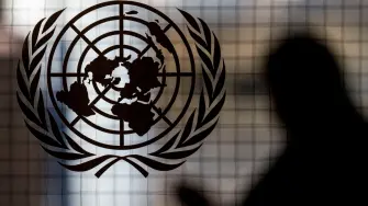 (FILES) A person walks past the UN logo at UN headquarters in New York City on February 8, 2024. All seven candidates to lead the United Nations received a vote of 