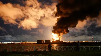 Personas observan el incendio de una terminal petrolera tras un ataque aéreo atribuido a drones ucranianos en San Petersburgo, Rusia.