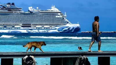 Un hombre pasea por el embarcadero de Mahahual en presencia de un crucero turístico. ArteAzul