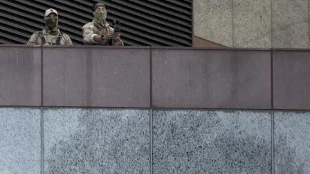Immigration and Customs Enforcement (ICE) Special Response Team (SRT) officers observe a demonstration from above while holding a sniper rifle outside the Metropolitan Detention Center, as protests continue in response to federal immigration operations in Los Angeles on June 13, 2025. Armed Marines arrived on the streets of Los Angeles on June 13, part of a large deployment of troops ordered by Donald Trump that has raised the stakes between the US president and opponents criticizing him of growing authoritarianism.Men in fatigues and carrying semiautomatic rifles were seen around a federal building, where passersby questioned why they were in an area 11 miles (18 kilometers) from the protests against immigration raids. (Photo by ETIENNE LAURENT / AFP)
