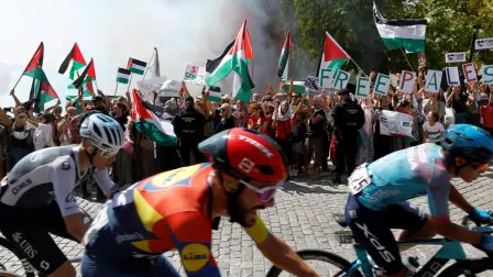 El grupo avanza mientras manifestantes pro-palestinos sostienen banderas.