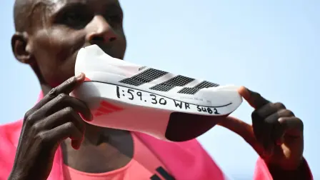 Kenya's Sabastian Sawe poses with his new world record time written on his running shoe at the finish of the 2026 London Marathon in central London on April 26, 2026. Kenya's Sabastian Sawe broke the two-hour mark for the first time in history on Sunday in winning the London Marathon. (Photo by JUSTIN TALLIS / AFP) / Restricted to editorial use - sponsorship of content subject to LMEL agreement.
